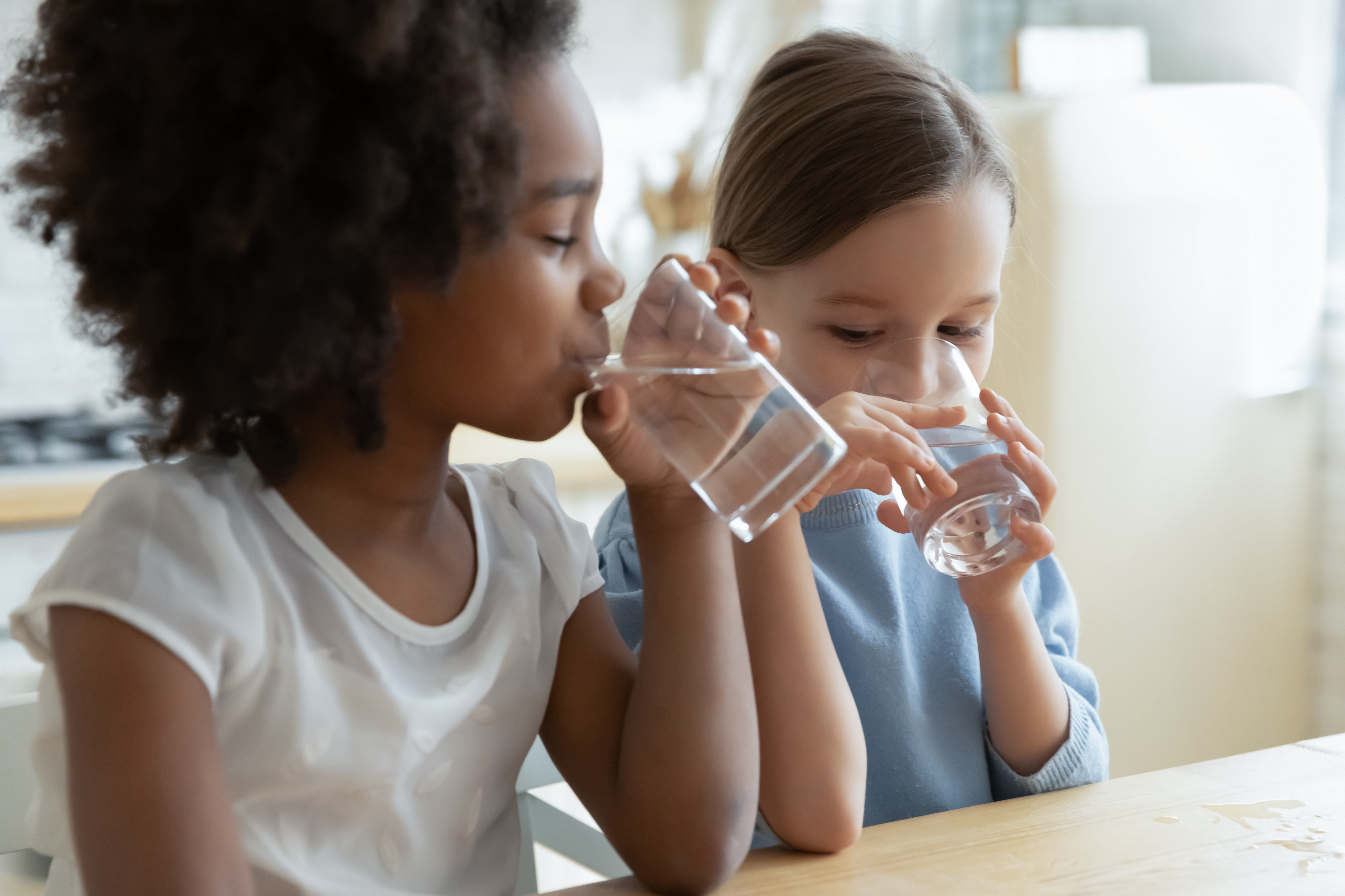 Zwei junge Mädchen trinken ein Glaß Wasser