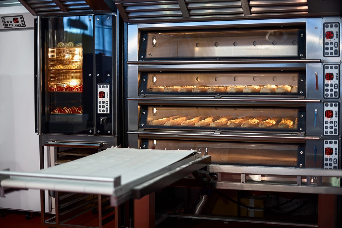 Bakkerijoven met meerdere lagen waarin broodjes worden gebakken, naast een aparte oven met brood zichtbaar.