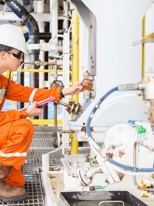 Kiwa engineer inspecting machinery on an oil, gas and chemicals platform