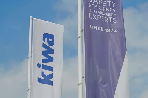 Twee wapperende vlaggen van Kiwa en Vinçotte tegen een blauwe lucht, met de teksten ‘creating trust driving progress’ en ‘Safety Efficiency Sustainability Experts’.