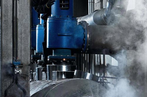 Industriell röranläggning med stora blå ventiler, metallrör och ånga i ett maskinrum - Kiwa håller i en kurs gällande FEM-analys av tryckkärl.