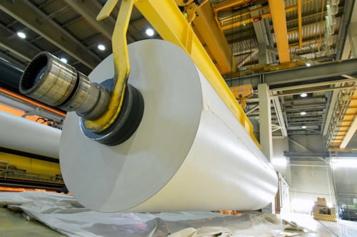 Produktion av papper i ett bruk - pappersrulle på en kran.