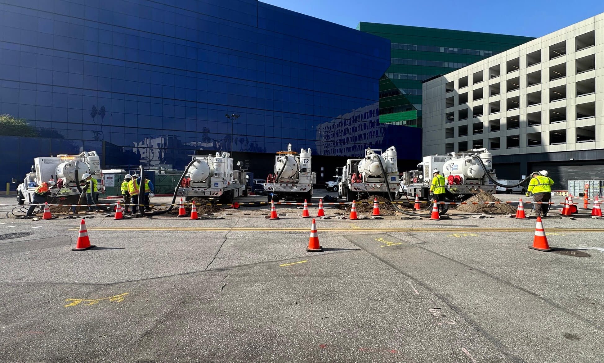 Construction workers with heavy equipment and orange traffic cones in front of modern office buildings