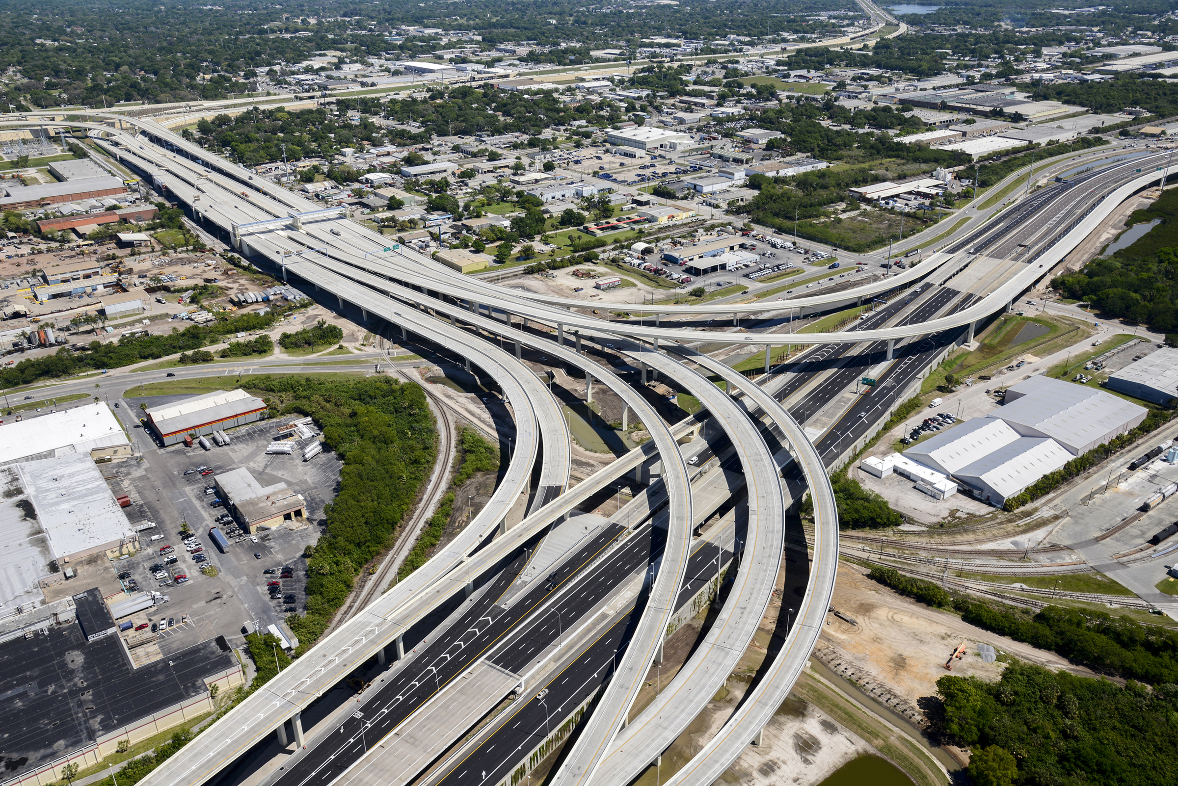 Aerial view of a large urban highway interchange with multiple elevated overpasses and surrounding commercial buildings.